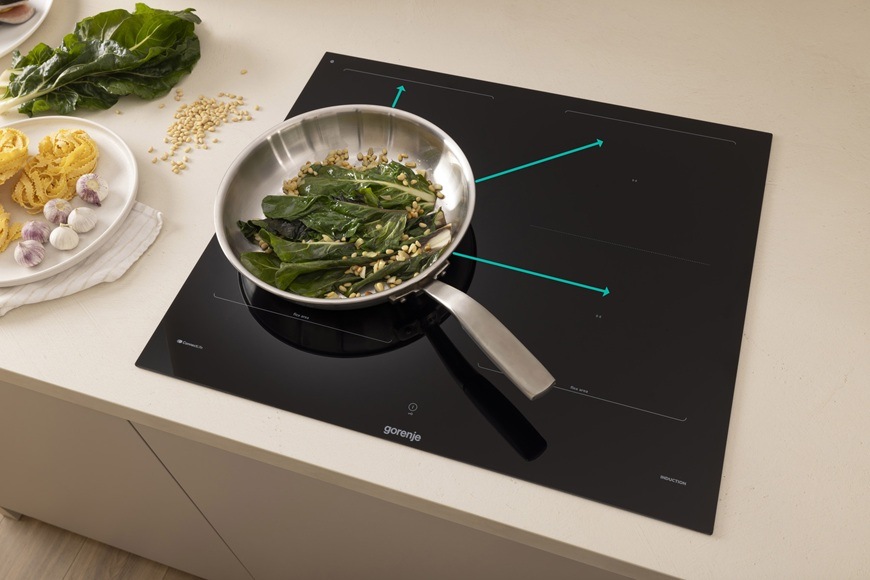 Indukční varná deska Gorenje G800 GI6443BSCWF černá Indukční varná deska Gorenje GI6443BSCWF je zabudovaná v moderní kuchyni. Na desce se v pánvi připravuje jídlo. Modré šipky graficky ukazují, že lze pánev přesouvat na jiné varné zóny bez ztráty nastavení výkonu a času.