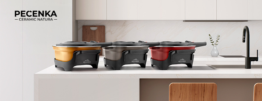 Tři elektrické pečicí hrnce PEČENKA CERAMIC NATURA s keramickým povrchem, v barevných variantách béžová, šedá a červená, vystavené na bílé kuchyňské lince