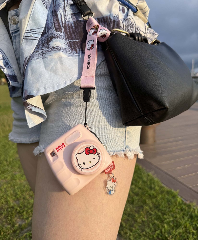 Digitální fotoaparát Yashica x Hello Kitty Mini Digital Camera růžový Kompaktní fotoaparát Yashica x Hello Kitty zavěšený na popruhu připnutém k kabelce