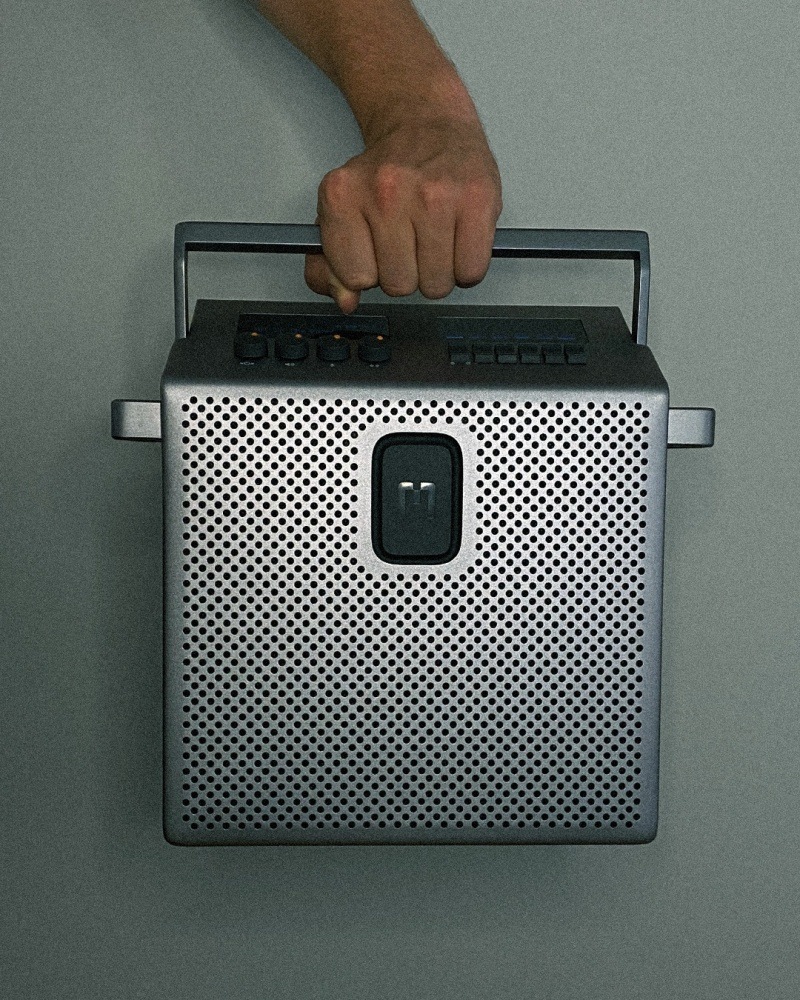 Přenosný reproduktor Mondo Speaker Medium šedý Ruka drží Přenosný reproduktor Mondo Speaker Medium