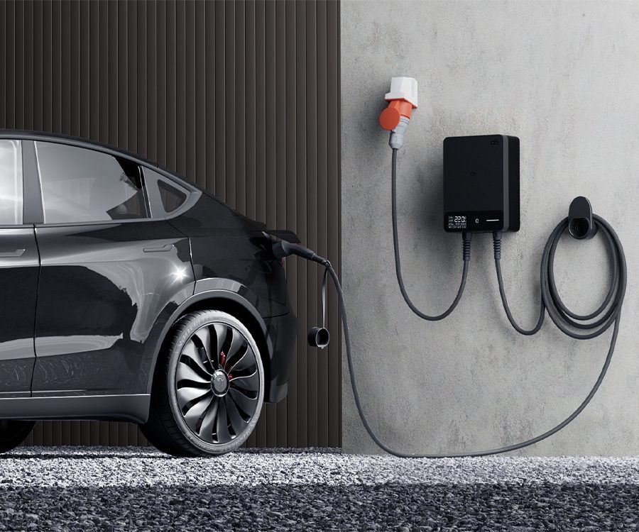 Černé elektrické auto nabíjené pomocí wallboxu dé namontovaného na zdi.