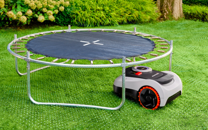 Robotická sekačka Segway Navimow i220E LiDAR seká trávník u zahradní trampolíny
