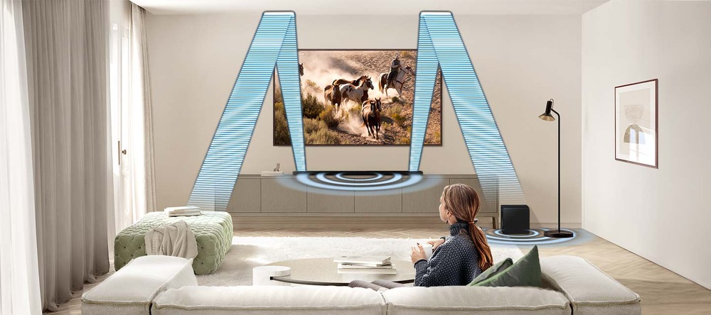 Soundbar Samsung HW-S800D je připevněný na zdi pod TV Samsung v obývacím pokoji, v popředí sedí žena na pohovce a sleduje televizi, ze soundbaru vychází modrá kolečka a modré čáry znázorňující prostorový zvuk