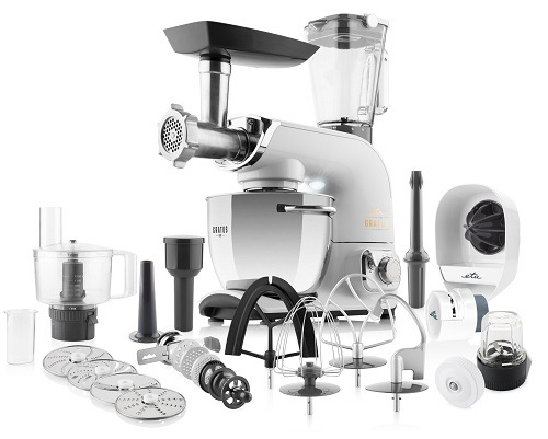 Celokovový kuchyňský robot ETA Gratus Evo Max II v bílé barvě zobrazený se všemi nástavci: skleněný mixér, food processor, mlýnek na maso, hnětací háky, šlehací metly a disky na strouhání