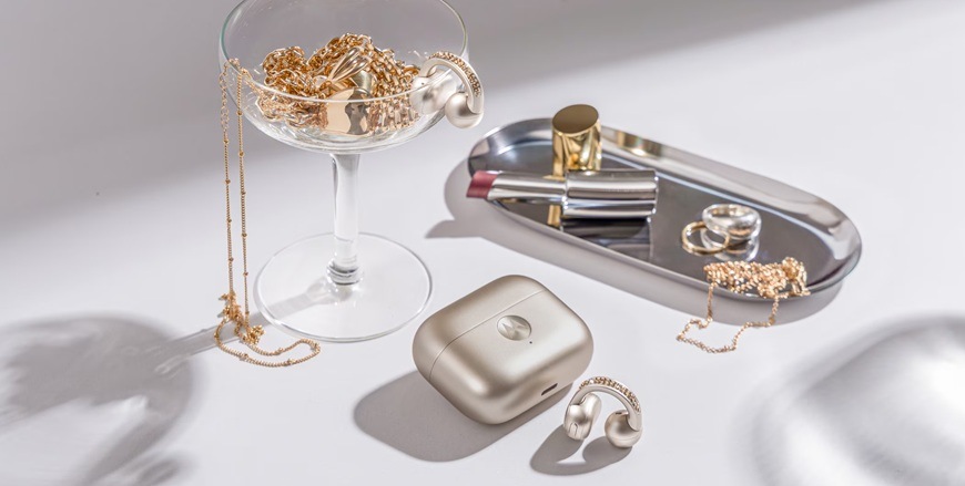 Sluchátka Motorola Moto Buds Loop Swarovski® Crystals béžová Detail obrázku sluchátek s pozadím a kosmetickými doplňky.