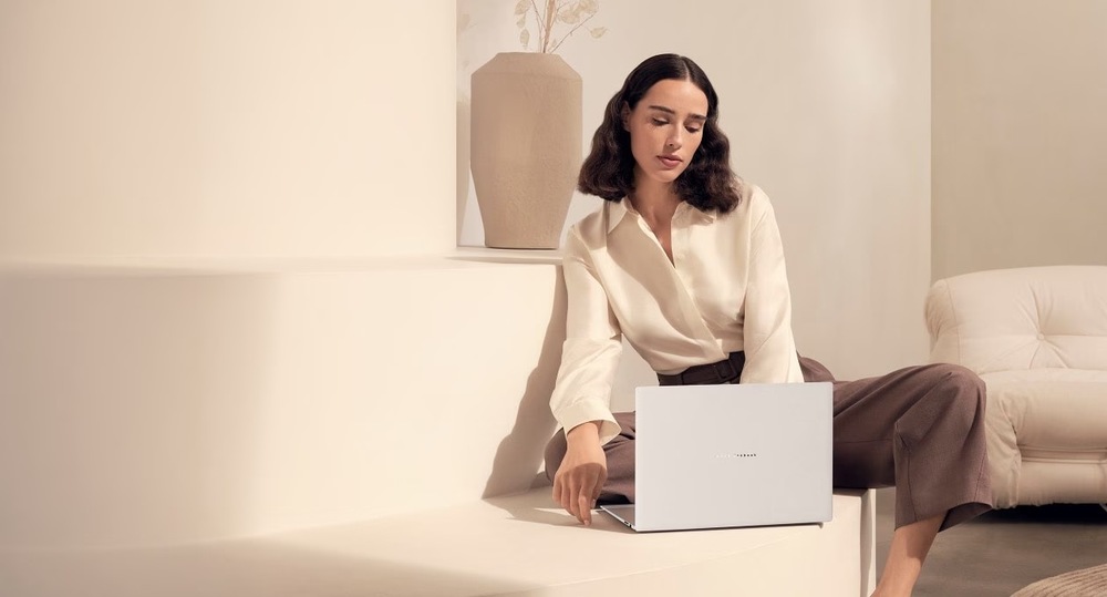 Žena sledující obsah na laptopu Asus Zenbook S16 v moderním interiéru