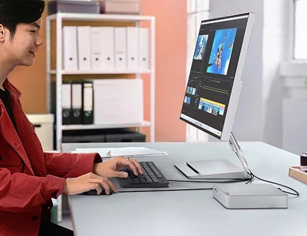 PC mini Lenovo IdeaCentre Mini 01IRH10R šedý Muž pracující s fotografiemi na monitoru, ke kterému je připojený mini stolní počítač Lenovo IdeaCentre Mini