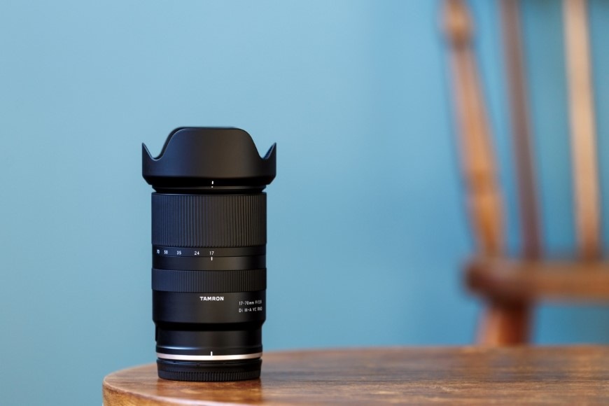 Objektiv Tamron 17-70 mm f/2.8 Di III-a RXD (Nikon) černý Zátiší s objektivem Tamron 17–70 mm f/2.8 Di III-a RXD stojícím na stole