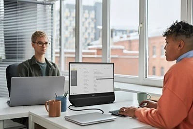 Žena a muž ve sdílené kanceláři pracují každé na jedné straně duální obrazovky Philips