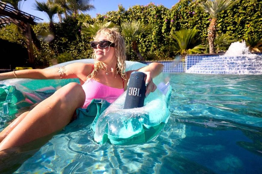 Přenosný reproduktor JBL Grip modrý Žena v bazénu, poslouchající přenosný reproduktor JBL GRIP