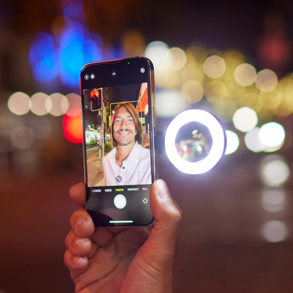 Ruka drží smartphone se světlem SnapPocket a v pozadí je tma