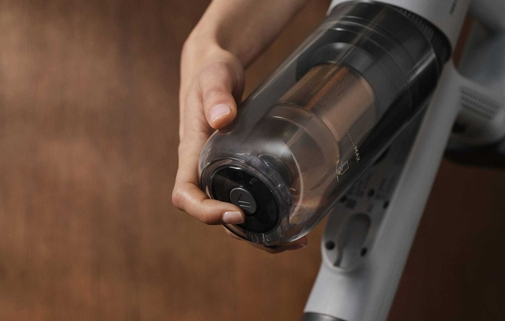 Tyčový vysavač Electrolux 700 Hygienic EP72H21WET modrý Žena stiskem tlačítka odděluje prachovou nádobku od těla vysavače.