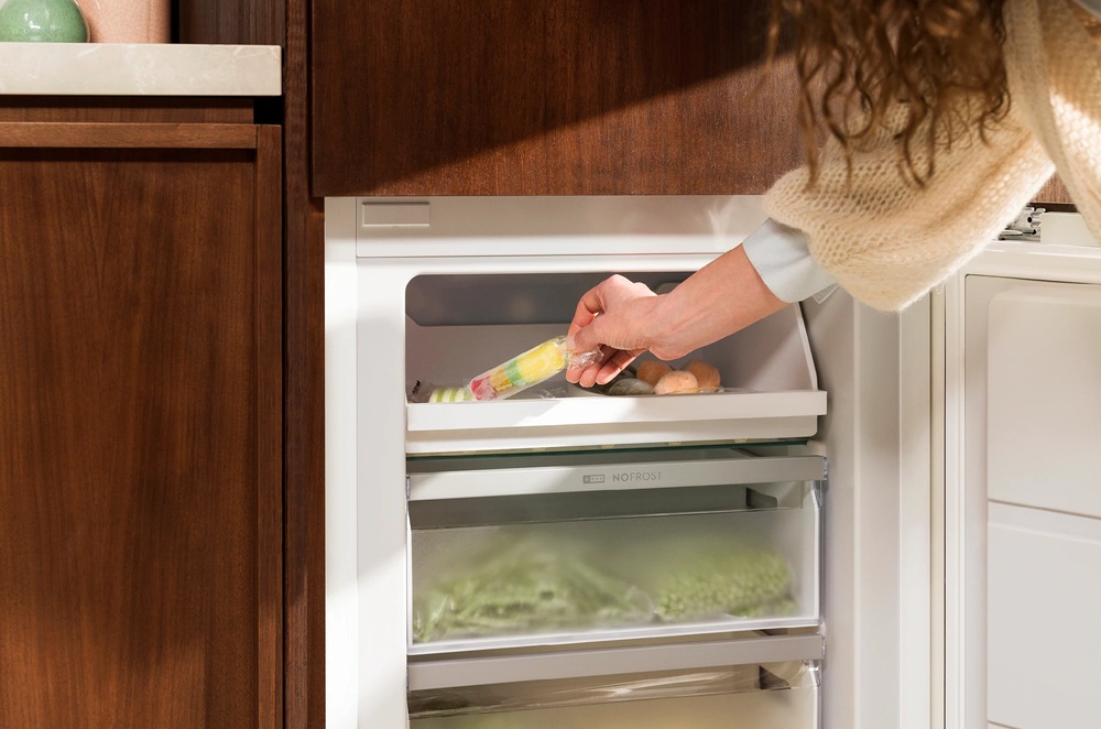 Žena si bere nanuk z mrazicí zásuvky lednice Electrolux.