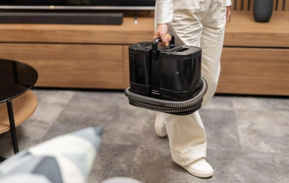 Tepovač koberců Hisense HSSC07A 2in1 Steam IQ černý člověk přenáší tepovač Hisense HSSC07A jako dukaz, že má kompaktní rozměry.