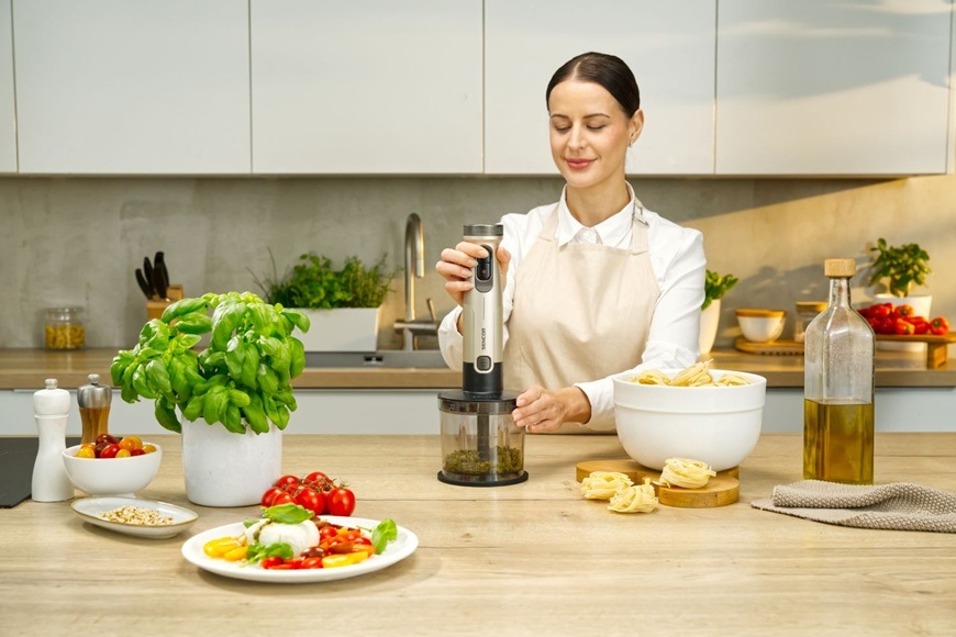 Žena za pomocí ponorného mixéru připravuje domácí pesto.