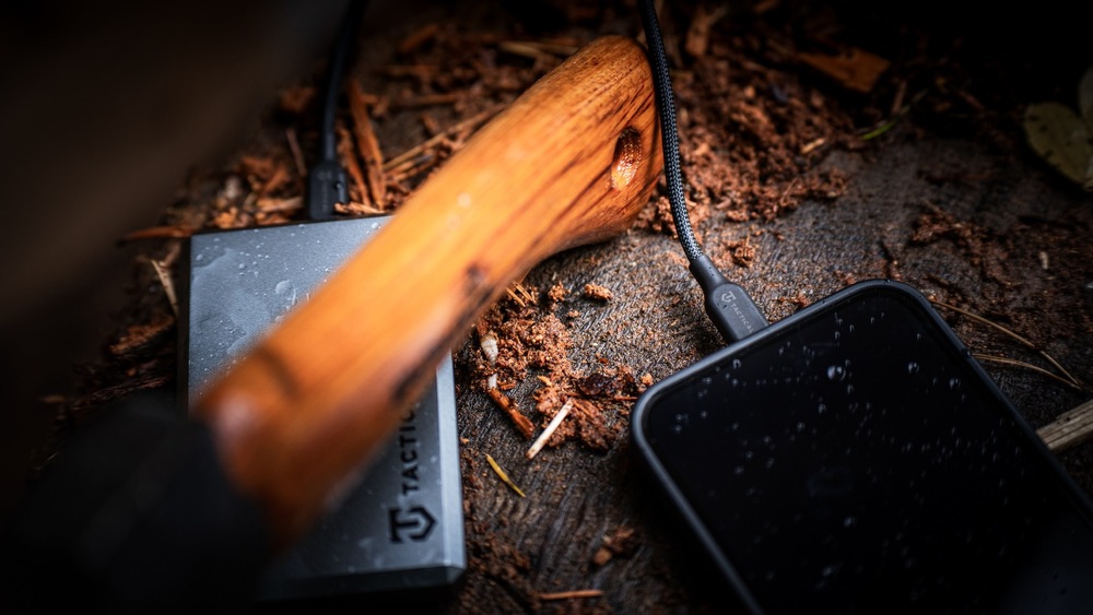 Kabel Tactical Stitch Thread USB-C/USB-C 0,3m černý Smartphone položený v přírodě napojený na powerbanku skrz kabel Tactical Stitch Thread