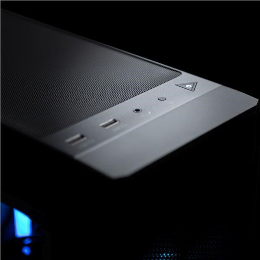 Detailní záběr na elegantní horní panel počítačové skříně za slabého osvětlení s USB porty, konektorem pro sluchátka a tlačítkem napájení s jemným modrým LED podsvícením.