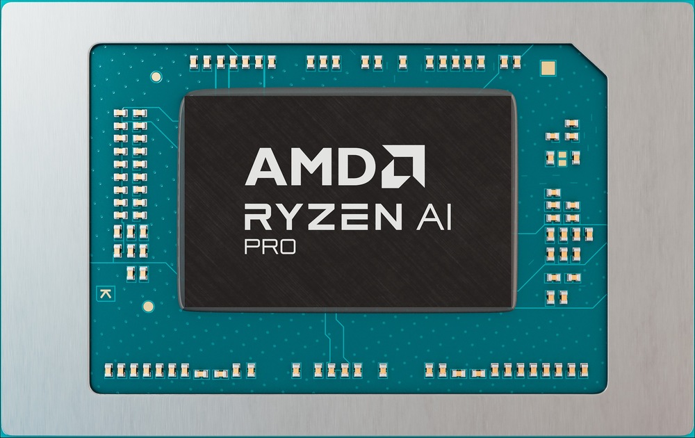 Detailní záběr procesoru AMD Ryzen AI Pro na modrozelené desce plošných spojů. Čip má stříbrné písmo a je obklopen několika zlatými tranzistory.