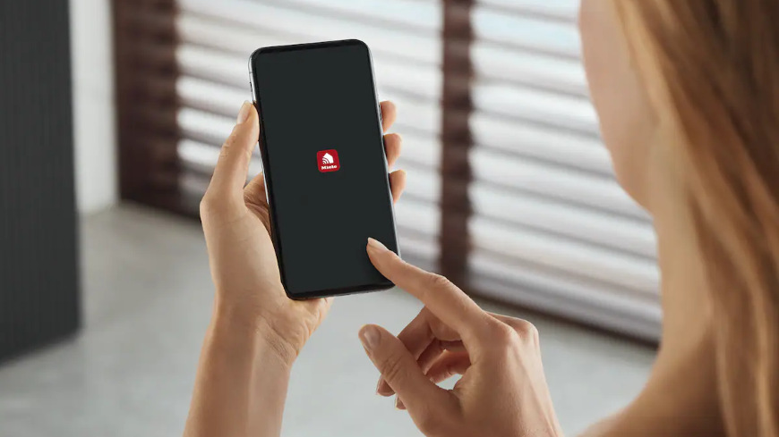 Trouba Miele H 7440 BM béžová Žena používá aplikaci Miele na svém chytrém telefonu