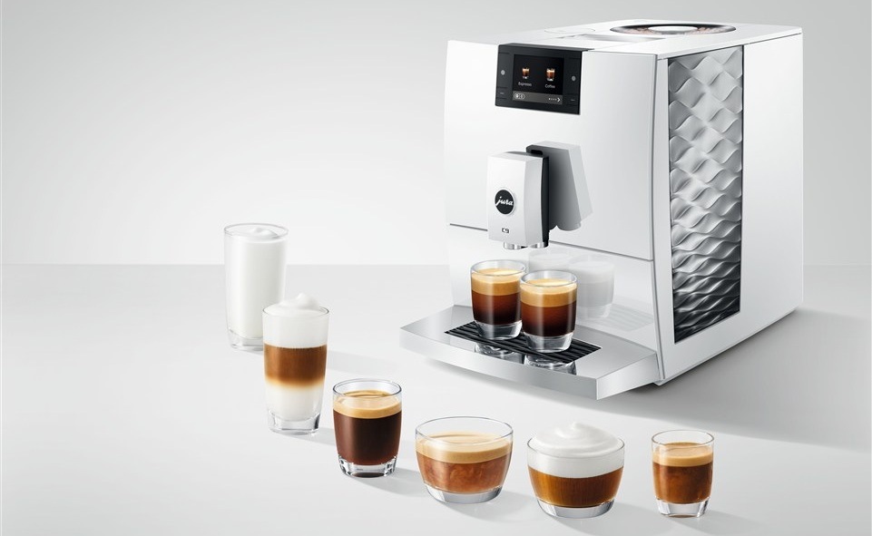 Automatický kávovar Jura C9 Piano White bílý Automatický kávovar Jura C9 Piano White chystá dvě sklenice kávy, před kávovarem stojí šest sklenic s různými druhy kávy
