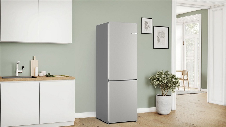 Zavřená lednice Bosch KGN362I1F v bílé kuchyni se zelenou stěnou, v pozadí jídelní stůl a židle