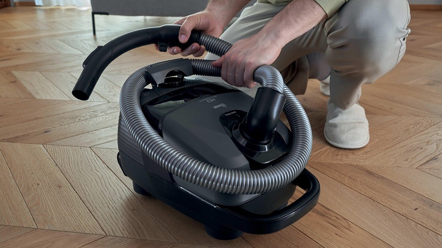 Podlahový vysavač Hoover HE210P 011 černý/tmavě šedý osoba motá hadici kolem vysavače Hoover HE210P 011
