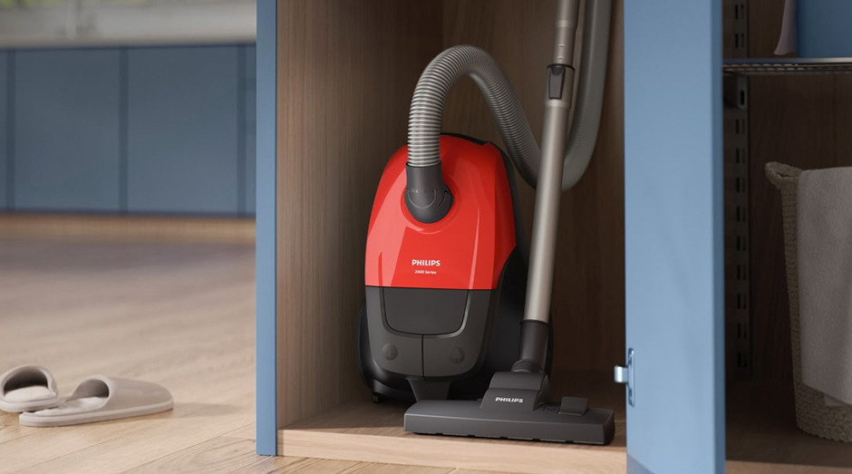 Kompaktní sáčkový vysavač Philips XD1111/10 1000 Series uložený ve skříni pro snadné skladování.