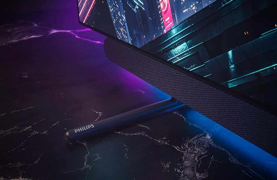 Televize Philips 65OLED911 Detail rohu integrovaného soundbaru televize Philips s vyraženým logem značky.