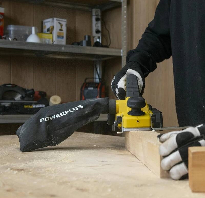 Práce s elektrickým hoblíkem Powerplus na hraně dřevěné desky v dílně
