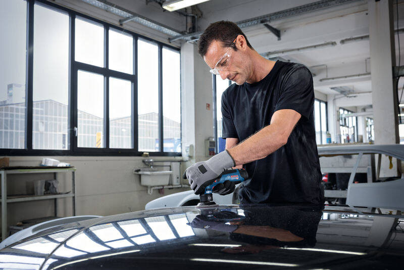 Excentrická bruska Bosch Professional GEX 12V-77 (bez baterie) Práce s akumulátorovou excentrickou bruskou Bosch na karoserii auta v autoservisu s ochrannými brýlemi