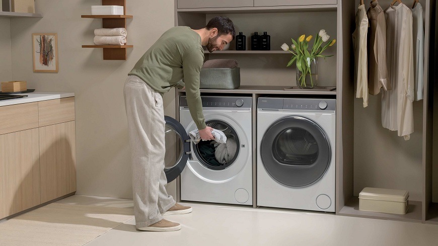 Pračka Haier HW90-B14367U-S bílá muž v prádelně dává do pračky haier HW90-B14367U-S prádlo