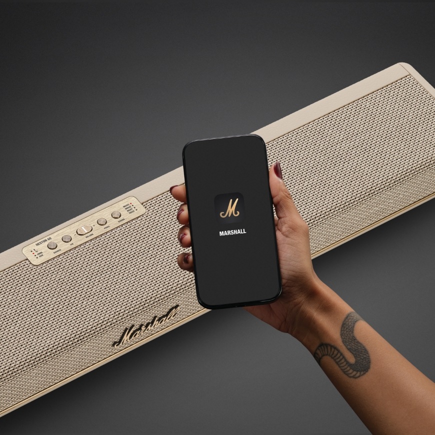 Ruka drží smartphone s mobilní aplikací kompatibilní se soundbarem Marshall Heston 60
