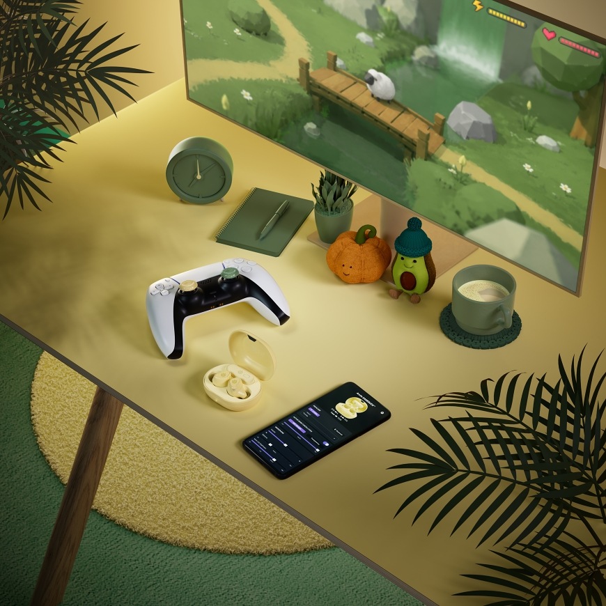 GameBuds Yuzu na herním stole s ovladačem PlayStation a mobilní aplikací na telefonu