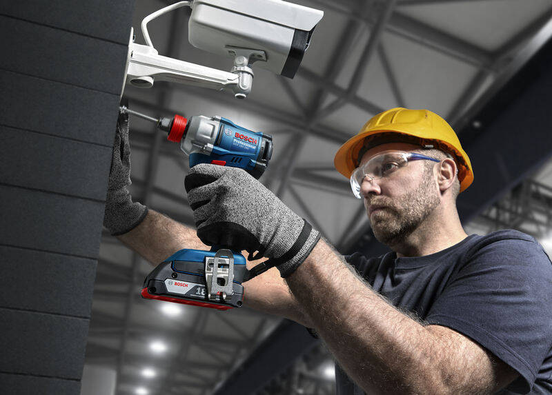 Muž v ochranných pomůckách používá při práci Rázový utahovák Bosch Professional GDX 18V-285