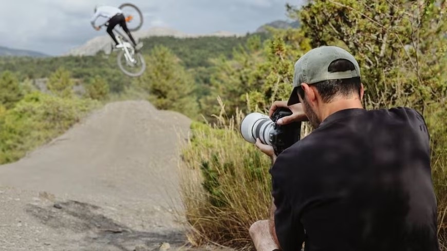 Digitální fotoaparát Canon EOS R6 Mark III + RF 24-105 mm f/4-7.1 IS STM černý Muž fotografující cyklistu s rychlou bezzrcadlovkou Canon EOS R6 Mark III