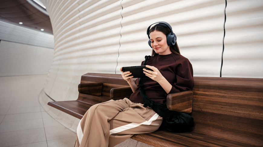 Headset SteelSeries Arctis Nova Pro Omni černý Žena s headsetem sedící na lavičce s mobilem