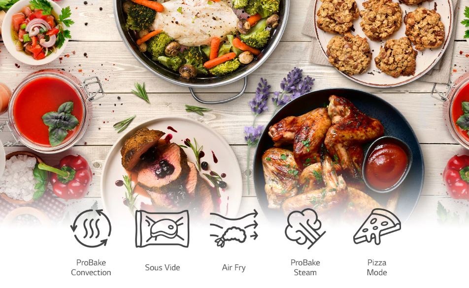 Trouba LG WSED7665B černá na stole leží připravené pokrmy z trouby LG, která nabízí mnoho programů pro různé typy přípravy: Sous Vide, Air Fry, Pára, Pizza, ... Na obrázku vidíme rajskou polevku s bazalkou, zapečenou brokolici se zeleninou, štavnaté maso s brusinkami, pečená kuřecí křídla nebo ovesné placičky.