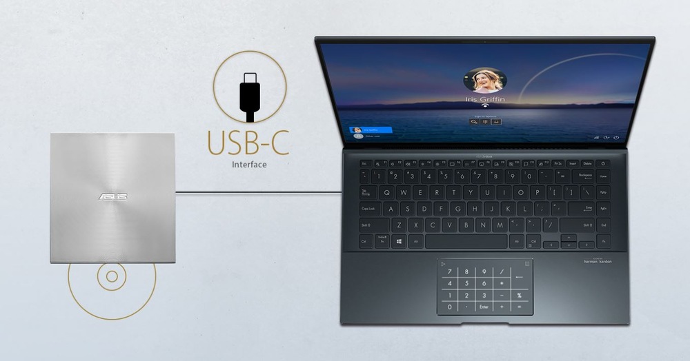 Notebook vpravo s přihlašovací obrazovkou profilu, připojený přes USB-C k externí DVD vypalovačce Asus po levé straně.