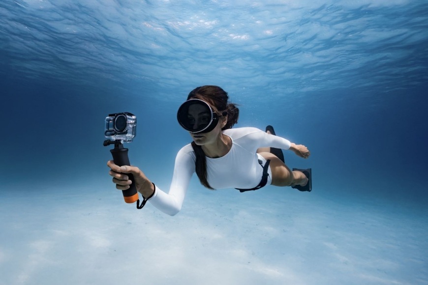 Sada příslušenství DJI Osmo Action 6 Diving Accessory Kit černá Žena plovoucí pod mořskou hladinou má akční kameru vybavenou příslušenstvím na potápění DJI Diving Accessory Kit