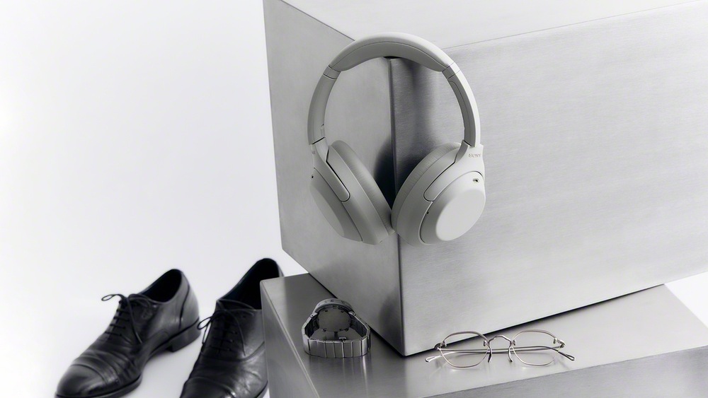 Sluchátka Sony WH-1000XM4C zavěšená na nábytku vedle obuvi