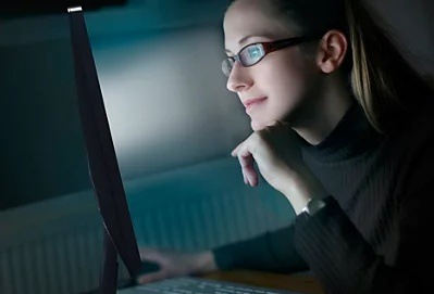 Monitor Philips 24B2U3601/00 černý Žena v tmavém prostředí sleduje obrazovku Philips s potlačením modrého světla