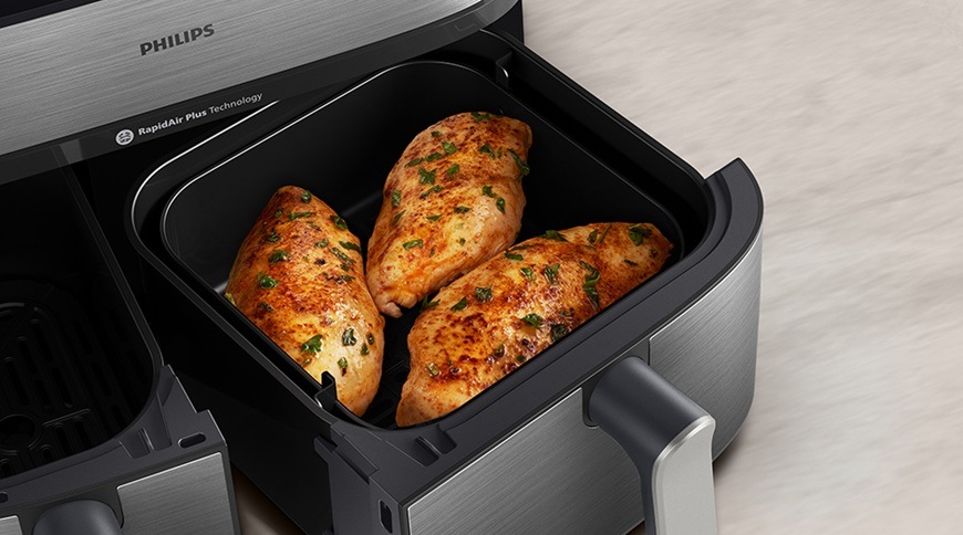 Fritéza horkovzdušná Philips Airfryer Dual Basket 5000 series 9 l, NA555/00 stříbrná Horkovzdušná fritéza Philips má povysunutý koš, ve kterém se právě ohřálo maso.