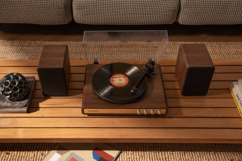 Gramofon Crosley C65 hnědý Gramofon Crosley C65 s externími reproduktory umístěný v interiéru, vinylová deska na talíři