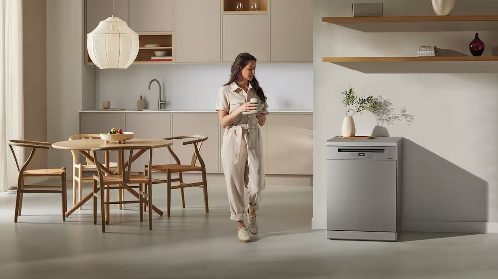 Myčka nádobí Miele G 5811 SC Active Plus v kuchyni, u myčky stojí žena s kávou