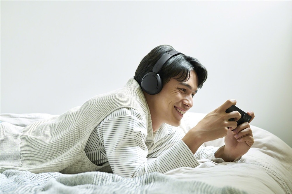 Muž leží na posteli se Sluchátky Sony WH-CH530