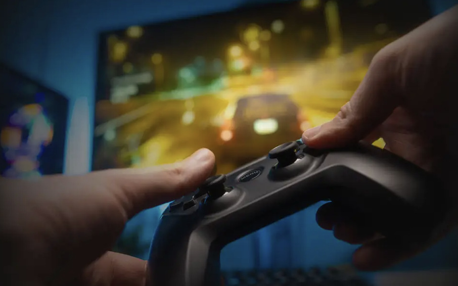 Hraní závodní hry na monitoru MSI MAG 272QPF E20 s ovladačem v rukou