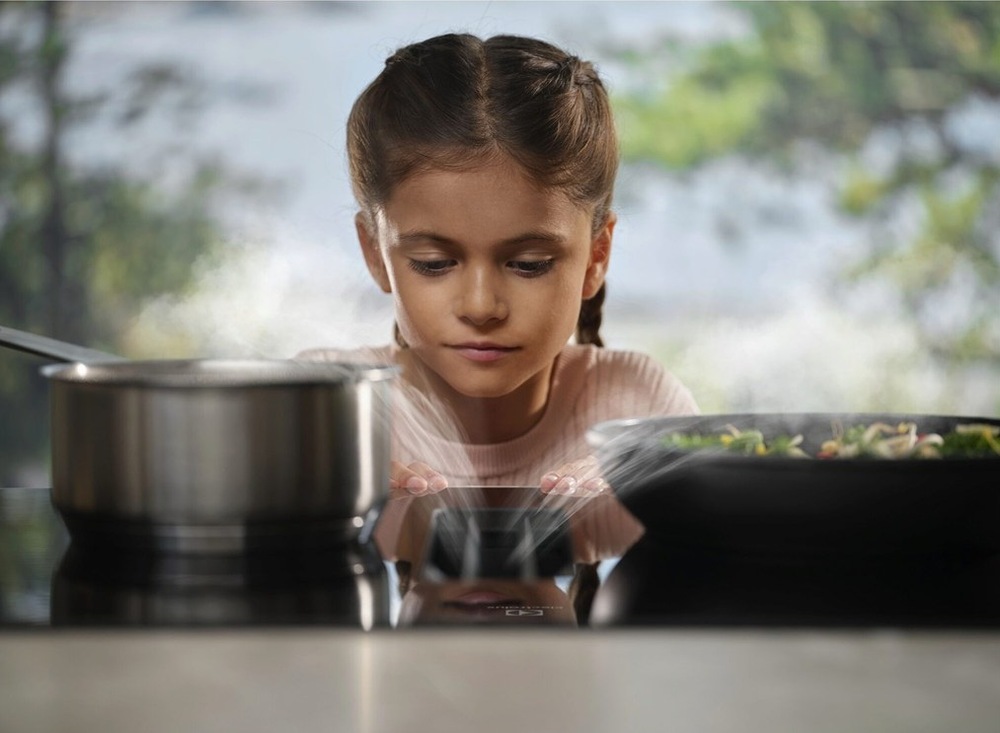 Holčička sleduje páru mizející v odsavači par desky Electrolux.