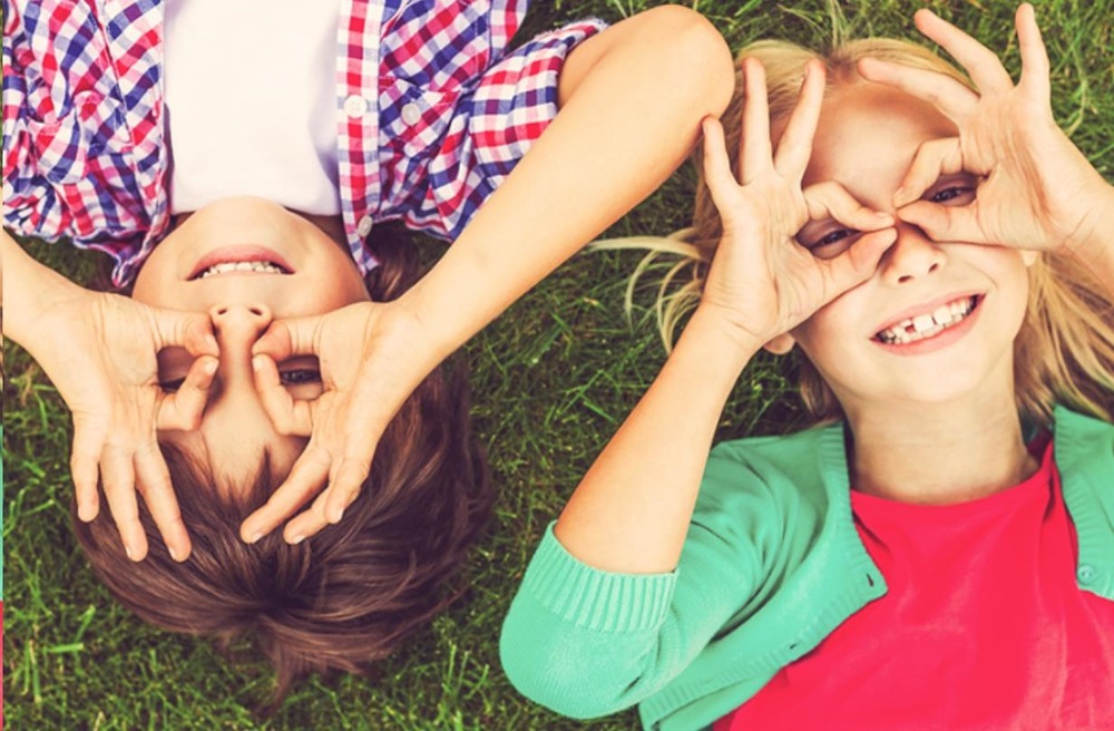 Digitální fotoaparát AgfaPhoto Realikids Cam 2 modrý Dvě děti si hrají a fotí se na trávě, ukázka použití fotoaparátu Realikids Cam 2.