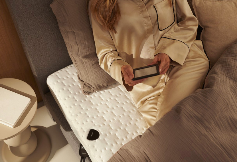 Žena relaxující na vyhřívací podložce Duux DXUB12 Snooze při večerním čtení v posteli