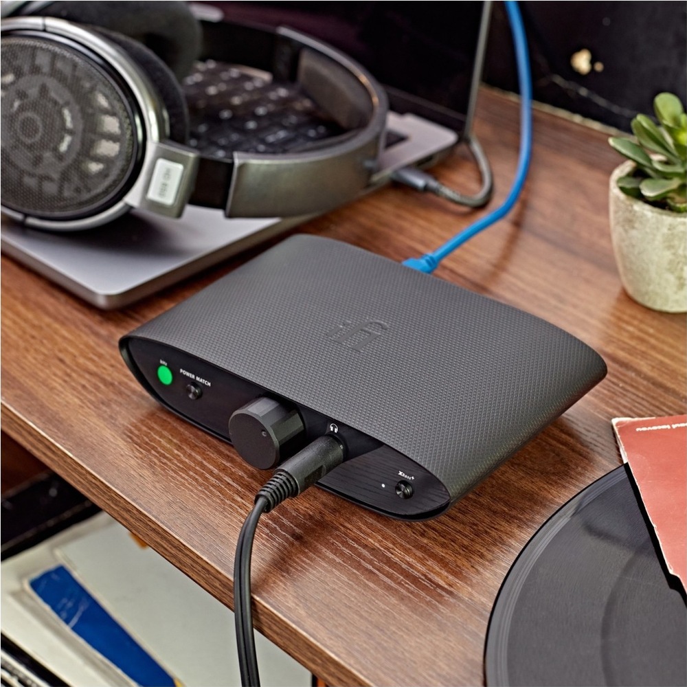 Sluchátkový zesilovač iFi audio ZEN Air DAC černý Sluchátkový zesilovač iFi Audio ZEN Air DAC na dřevěném stole, připojený ke sluchátkům a notebooku.